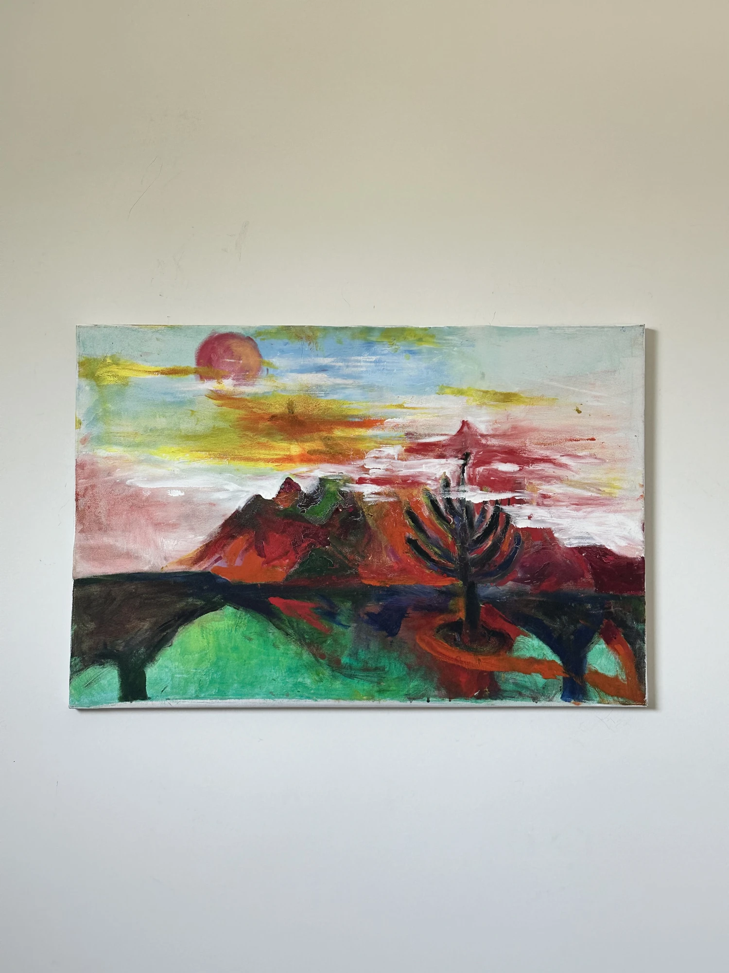 A dark branching tree before red and green hills, beneath a pink and yellow sky with a muted red sun. Sky + Tree, by Evelyn Altman.