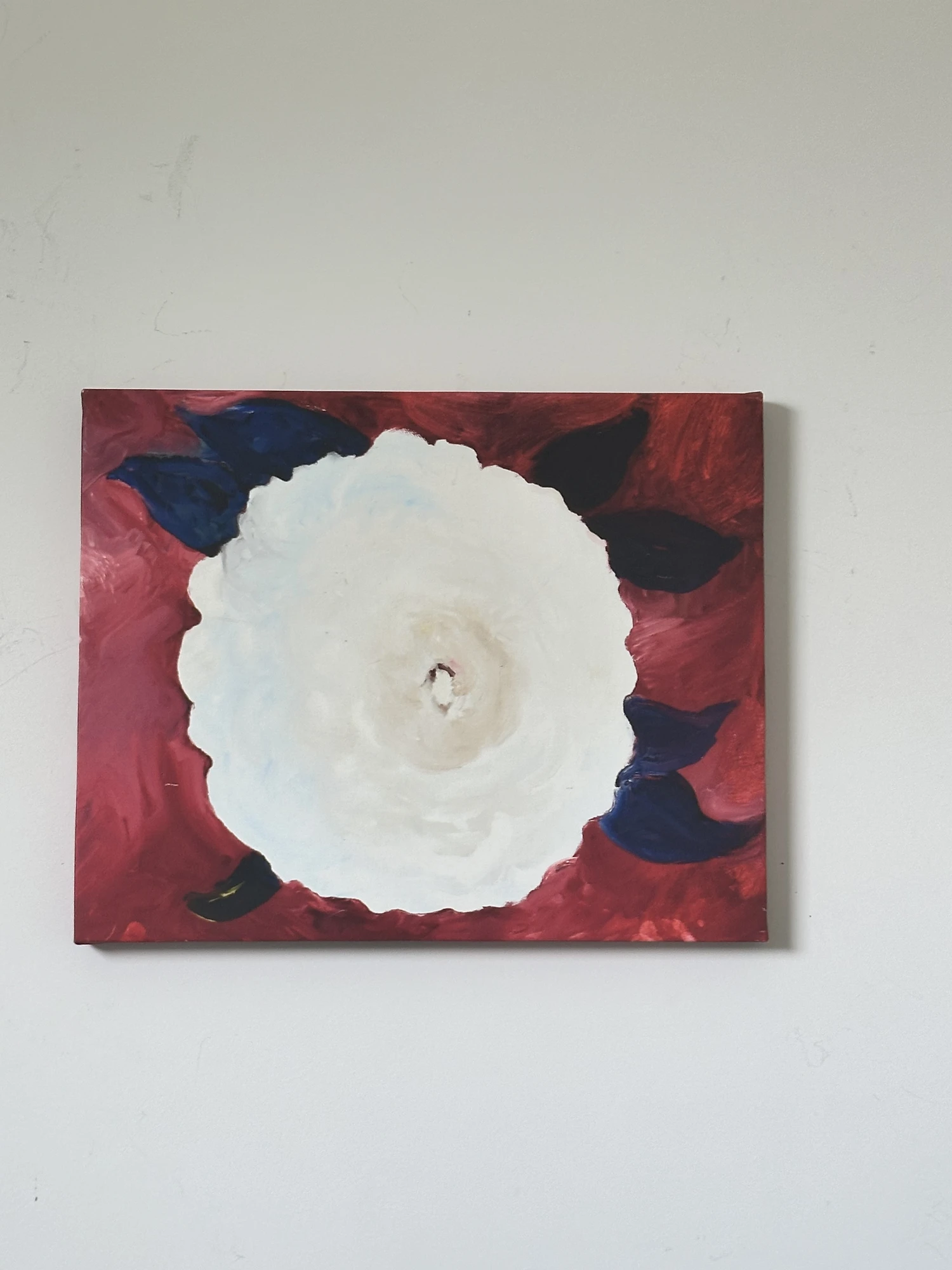 A large white flower surrounded by nearly black leaves on a deep red background. White Flower on Red Background, by Evelyn Altman.