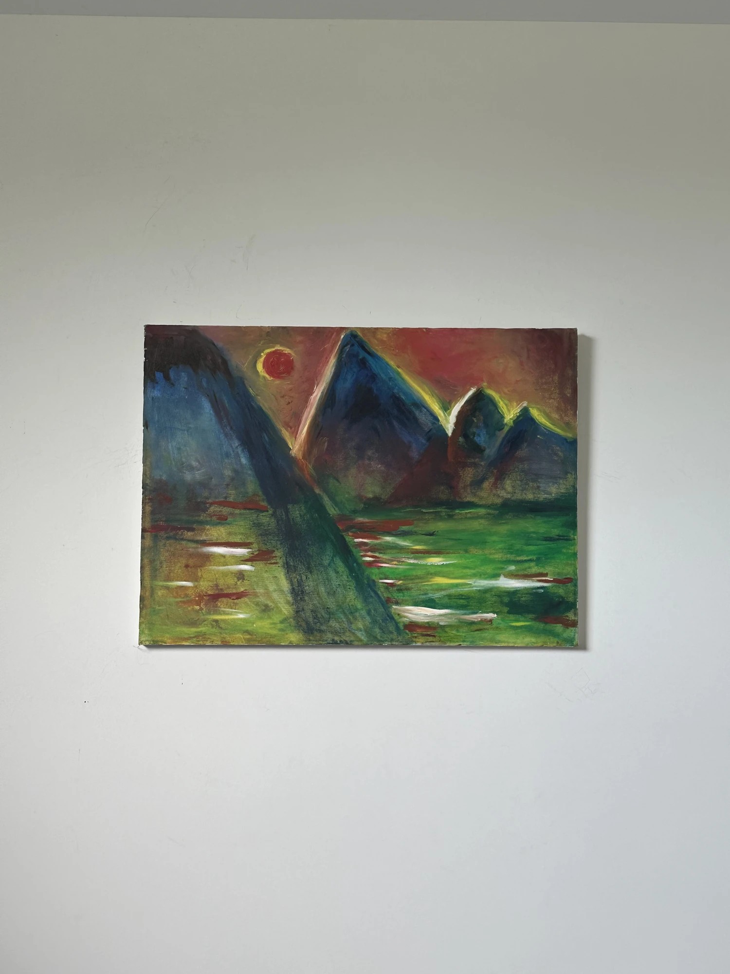 Blue mountain peaks and green reflections beneath a small yellow-red sun and a rust-colored sky. Mountains of Lake Tahoe California, by Evelyn Altman.