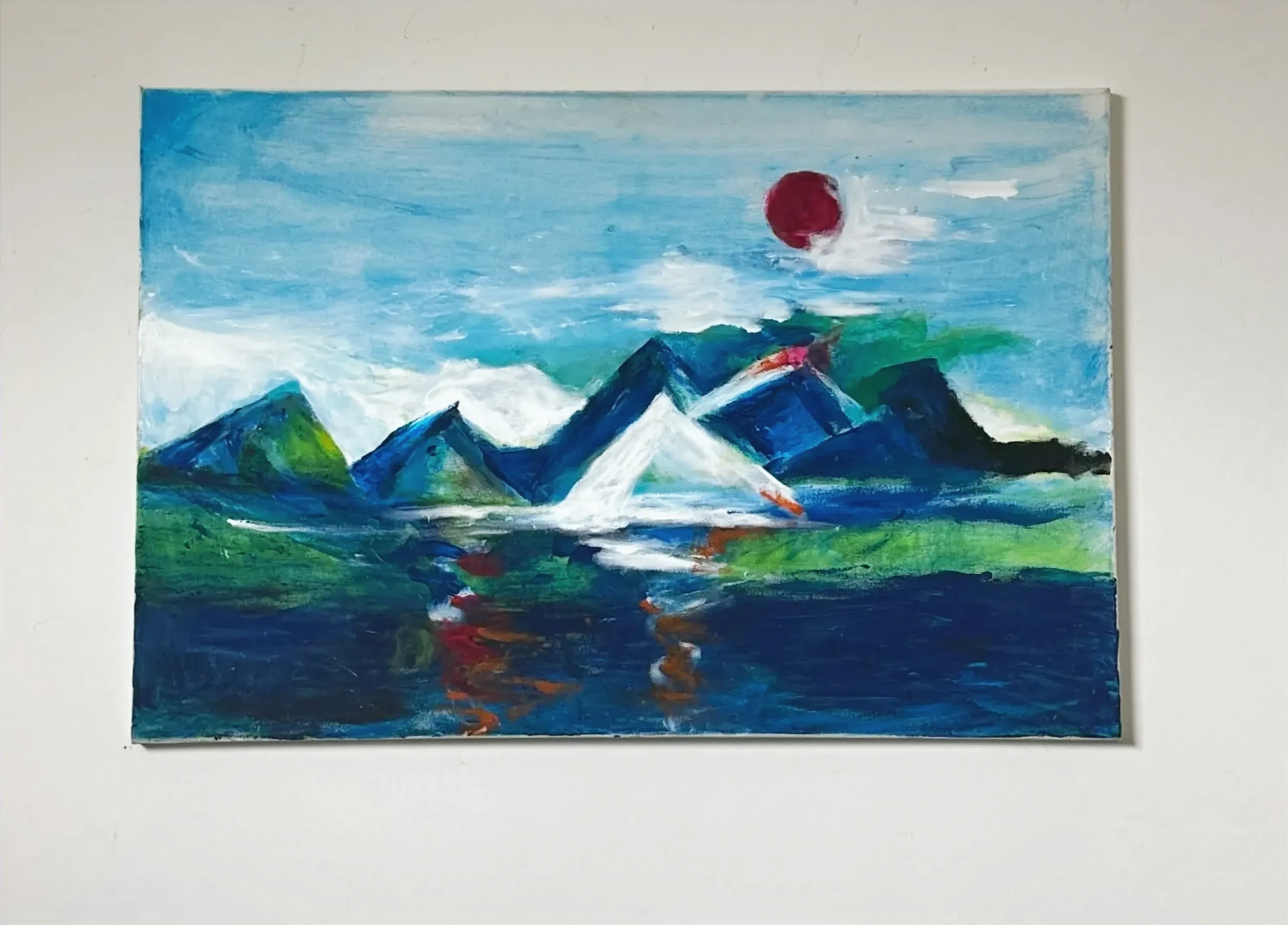 A chain of blue and green mountain peaks reflected in water beneath a small red sun. Sun Over The Mountains, by Evelyn Altman.
