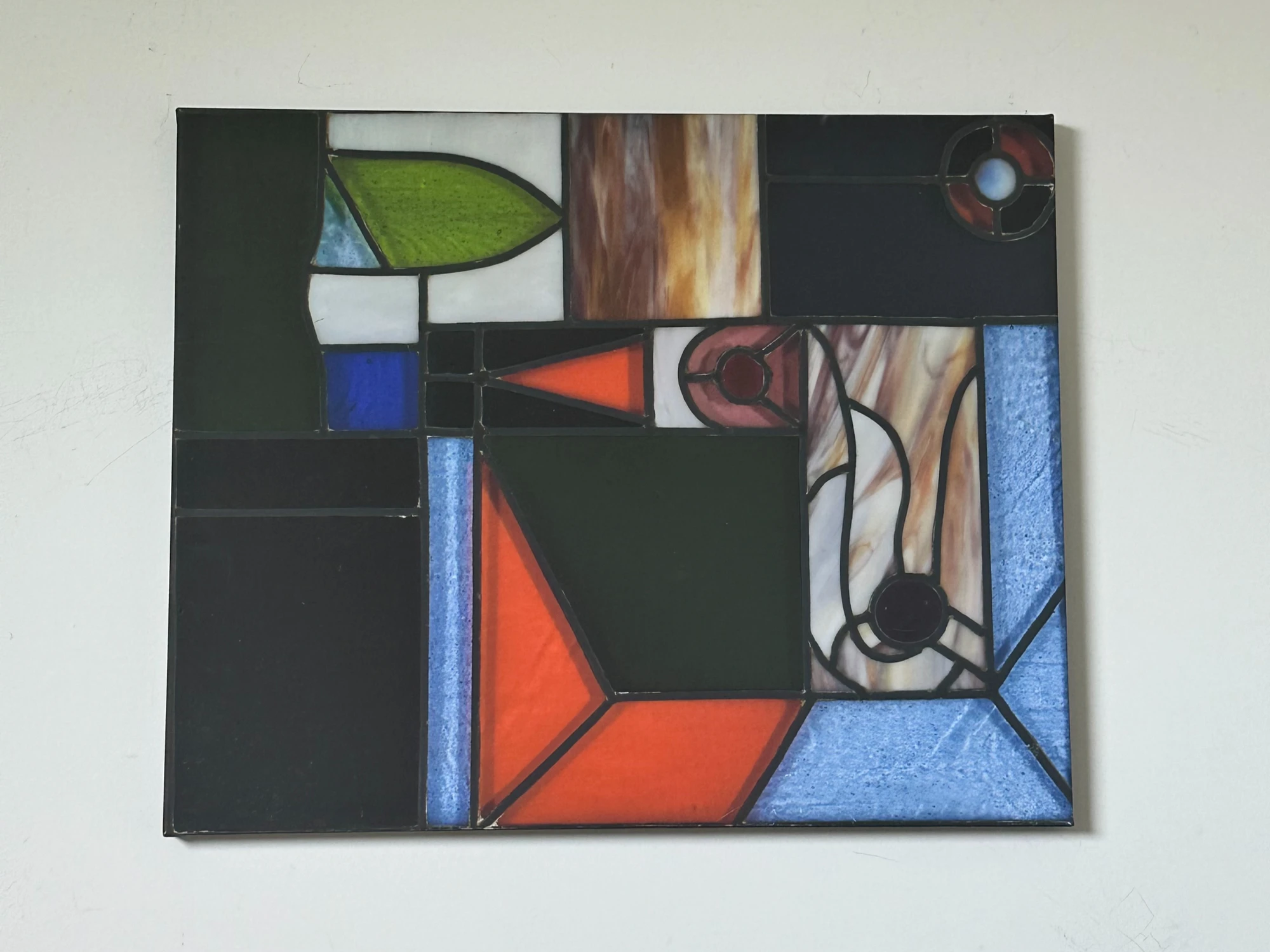 An arrangement of black rectangular areas, colored geometric panes and flowing outlined shapes. Church Window, by Evelyn Altman.