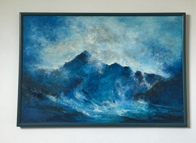 Foaming blue waves breaking around dark jagged rocks under a cloudy pale sky. Ocean Waves on The Rocks, by Evelyn Altman.