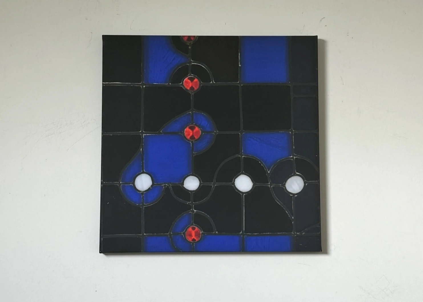 A geometric composition of blue and black rectangles with white circles and small red accents. Mind Puzzle, by Evelyn Altman.